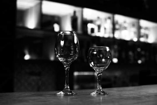 Two empty wine glasses on the bar counter black and white photo