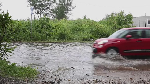 Driving Red Car Through Water in Flooded Street