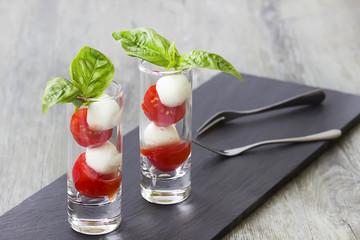 Salad Caprese in a white bowl on a gray wooden background. The concept of Mediterranean cuisine.