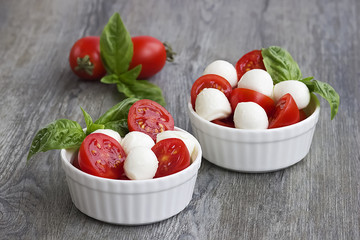 Salad Caprese in a white bowl on a gray wooden background. The concept of Mediterranean cuisine.