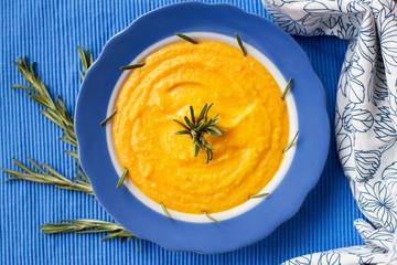 pumpkin cream soup in a blue plate on blue napkin, close-up