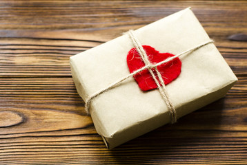gift box wrapped in kraft paper and red wooden heart on wooden table