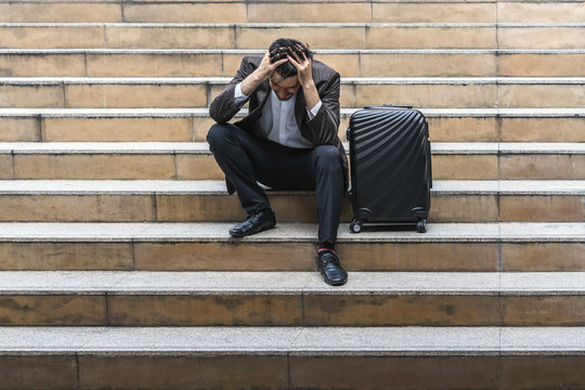Unemployed businessman stress sitting on stair, concept of business trip failure and unemployment problem, work life balance.