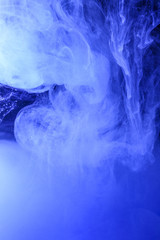 Blue dye swirling underwater creating a colourful abstract pattern