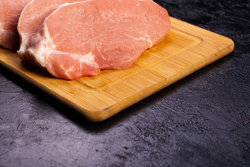 Close up on Fresh raw meat on wooden board on black wooden background. Gourmet food and fresh uncooked meal