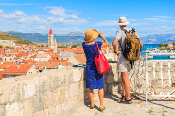 Naklejka premium Couple of unidentified elderly tourists taking picture of Trogir town from castle walls, Dalmatia, Croatia