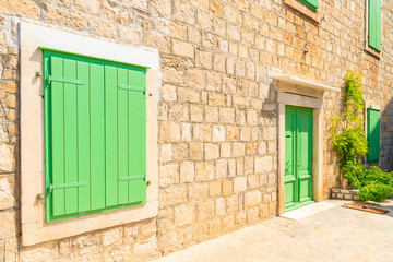 Fototapeta na wymiar Green window shutter and door of old house in Splitska village, Brac island, Croatia