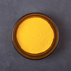 Turmeric powder in a bowl on a grey concrete background