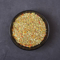 Spice mix - dill, parsley, basil, marjoram, oregano, saffron in a bowl on a grey concrete background