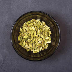 Cardamom seeds in a bowl on a grey concrete background