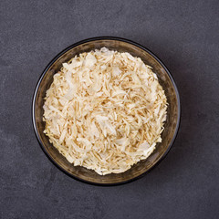 Dried onion in a bowl on a grey concrete background