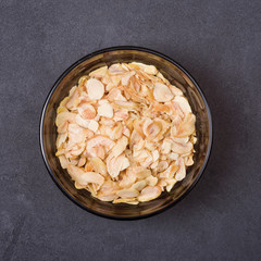 Dried garlic in a bowl on a grey concrete background