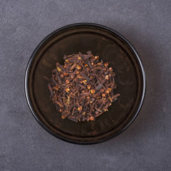 Clove in a bowl on a grey concrete background