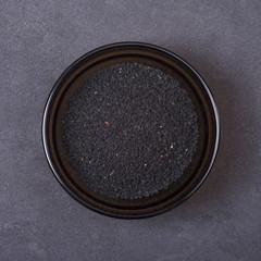 Black cumin seeds in a bowl on a grey concrete background