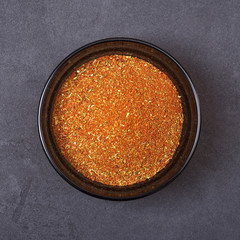 Spice mix - paprika, dried onion, white mustard, cumin, pepper in a bowl on a grey concrete background