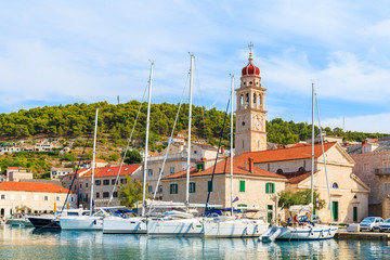 Yacht boats in Pucisca port with beautiful church on Brac island, Dalmatia, Croatia