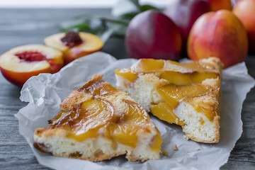 A pie with nectarines on a gray wooden table.