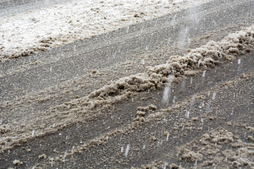 Close up muddy and glaze street with snow and traces from vehicles