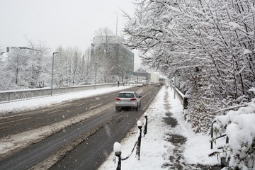 Cars driving along the mud street while it is snowing in the winter