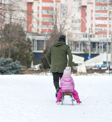 Fototapeta na wymiar Father sledding his little girl