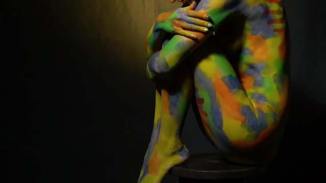 Naked woman in multi-colored patterns sitting on a high chair