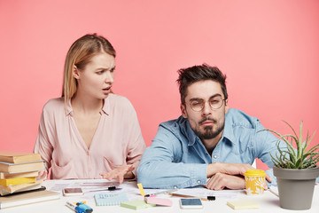 Indignant female student looks at her male groupmate who has sleepy expression in bewilderment, says that they have much work and no time for relaxation, asks to collect his strength to finish report