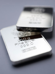 Silver bullion bars. Two fine silver bars on a grey background. Selective focus.