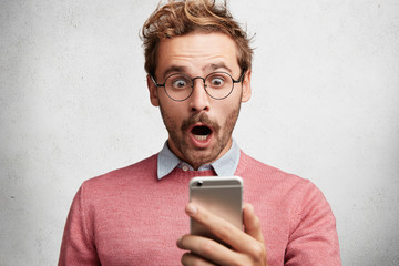 Shocked bearded male model surprised to recieve text message about his bills, realize that he is...