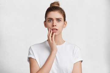 What cad! Lovely shocked female being in stupor as hears bad words from stranger, isolated over white background. Attractive young woman looks surprisedly and stupefied. Facial expressions concept