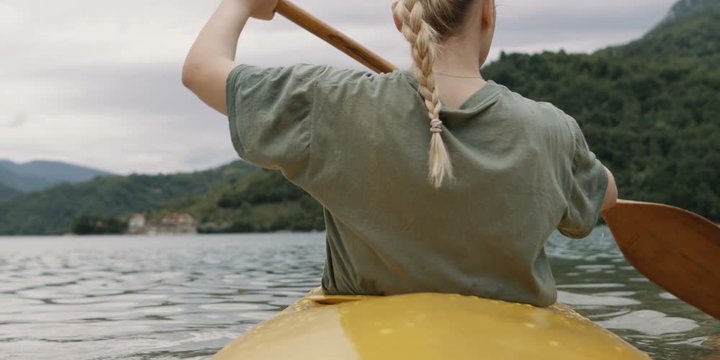 An attractive woman kayaking on lake. Shot on RED Helium 8K