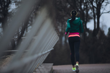 Rear view woman jogging outside in cold winter day