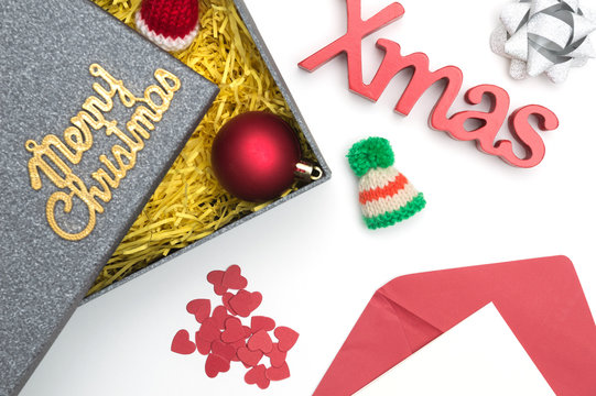 Merry christmas and X-mas text, fur hat, ball, ribbon, christmas card, heart in black gift box with yellow packaging material