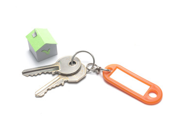 Keys with plastic tag and a green paper house: mortgage concept