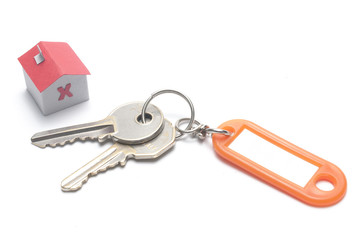 Keys with plastic tag and a green paper house: mortgage concept