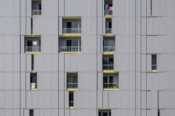 Modern gray facade of urban building with sun protect sliding metal panels on windows