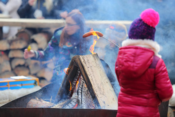 Dziewczynka piecze kiełbasę przy ognisku z mamą.