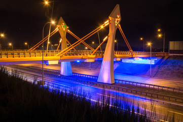 Modern illuminated bridge over street at night in Gdansk in Poland.