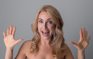 Sensation. Portrait of attractive overjoyed naked woman is standing with opened mouth and showing her palms to camera while screaming and expressing gladness. Isolated background
