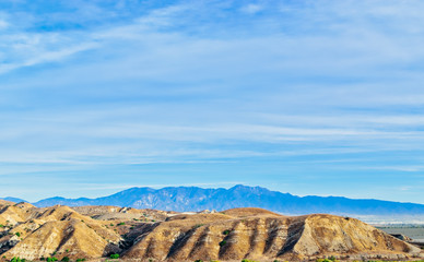 Southern California dry hills with mountains in background on clear day