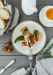 Omelet with vegetables with a cup of tea and a basket of bread on a gray wooden background top view