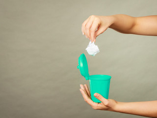 Woman putting paper into small trash can