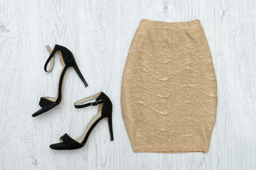 Golden skirt and black shoes. Fashionable concept. Wooden background.