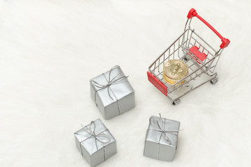 Bitcoin coins in shopping cart and gifts. White background