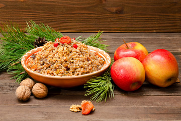 Obraz na płótnie Canvas Dish of traditional Slavic treat on Christmas Eve on brown wooden table. Pine branches, apples, walnuts.