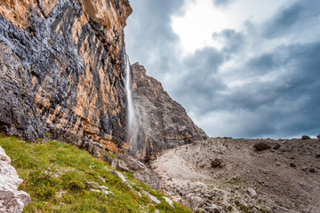 Waterfall at the foots of vertical and majestic western side of Tofana di Rozes Peak, Travenanzes Valley, Dolomites, Italy