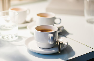 Several white coffee cups with freshly brewed coffee with a beautiful cream served in vintage 90s...