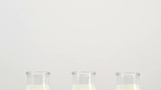 three milk bottles on white background without tags. Checkered red cloth accent. Slide shot from bottom up. Free space concept