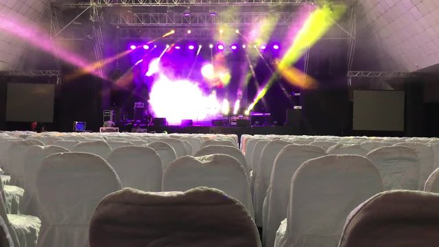 Tilt up from empty seats to a stage before a concert during sound check