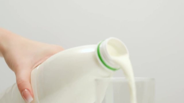 Woman untwists a plastic bottle of milk and pours it in a glass. Milk preservation and pasteurization concept