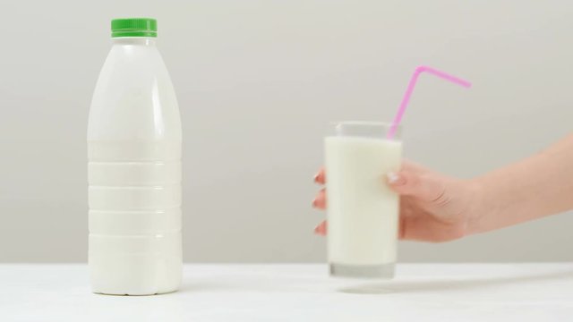 Healthy and tasty milkshake. Plastic bottle and a glass with a straw on white background